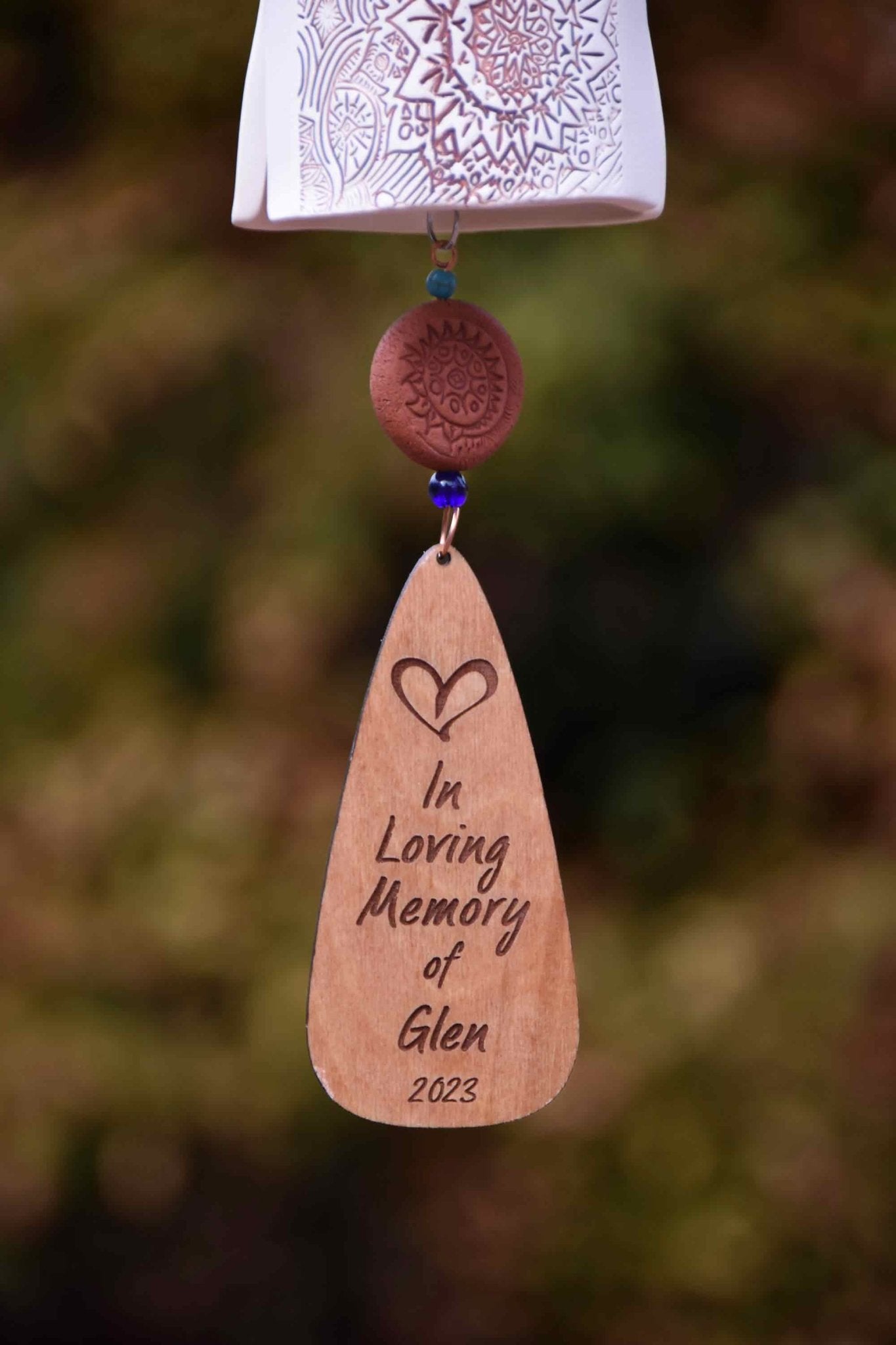 Custom engraved wooden wind sail paired with rustic ceramic memorial chime